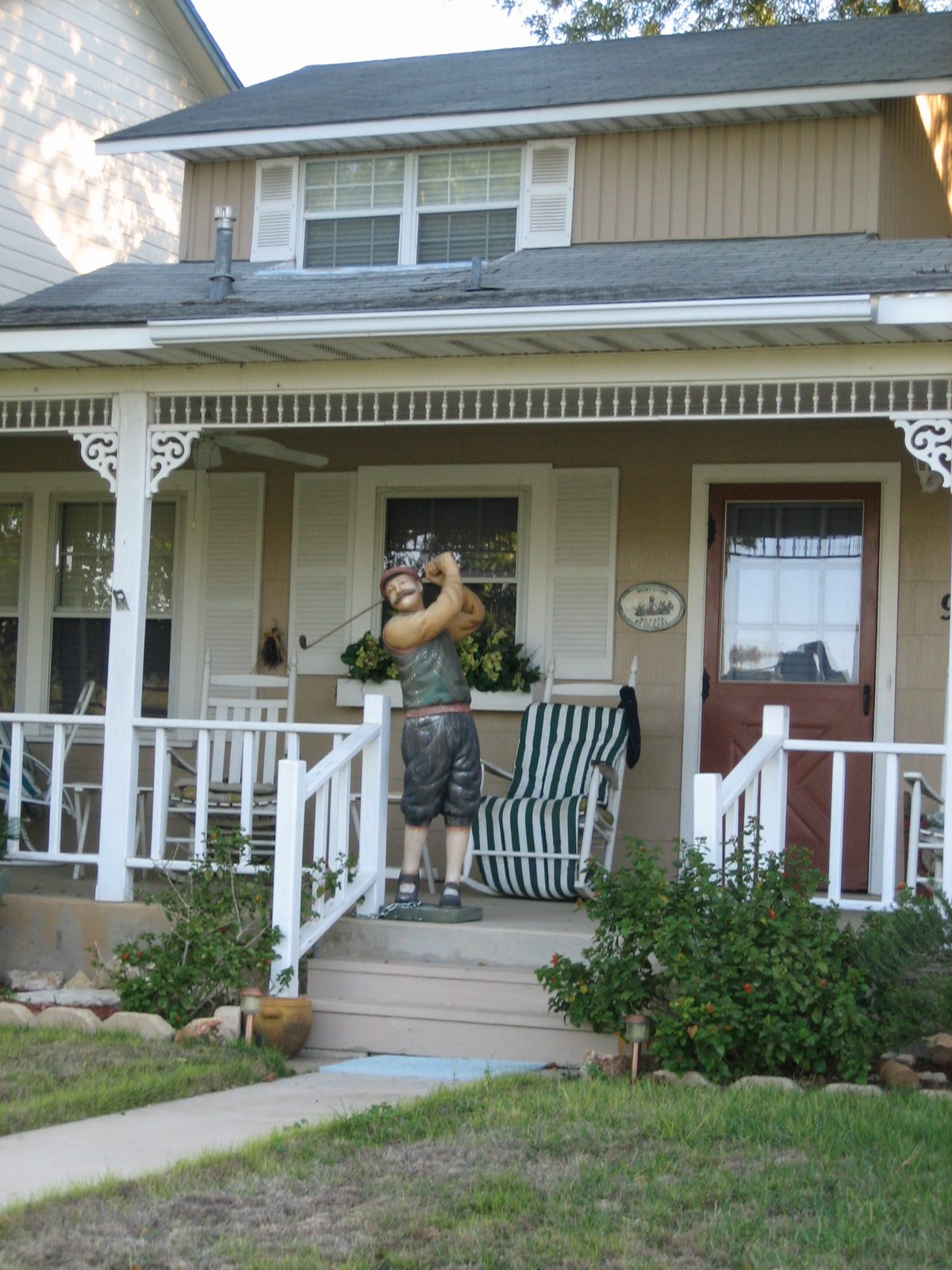 Kind of weird-looking fake golfer man standing on the porch of a house along the course.  I was...