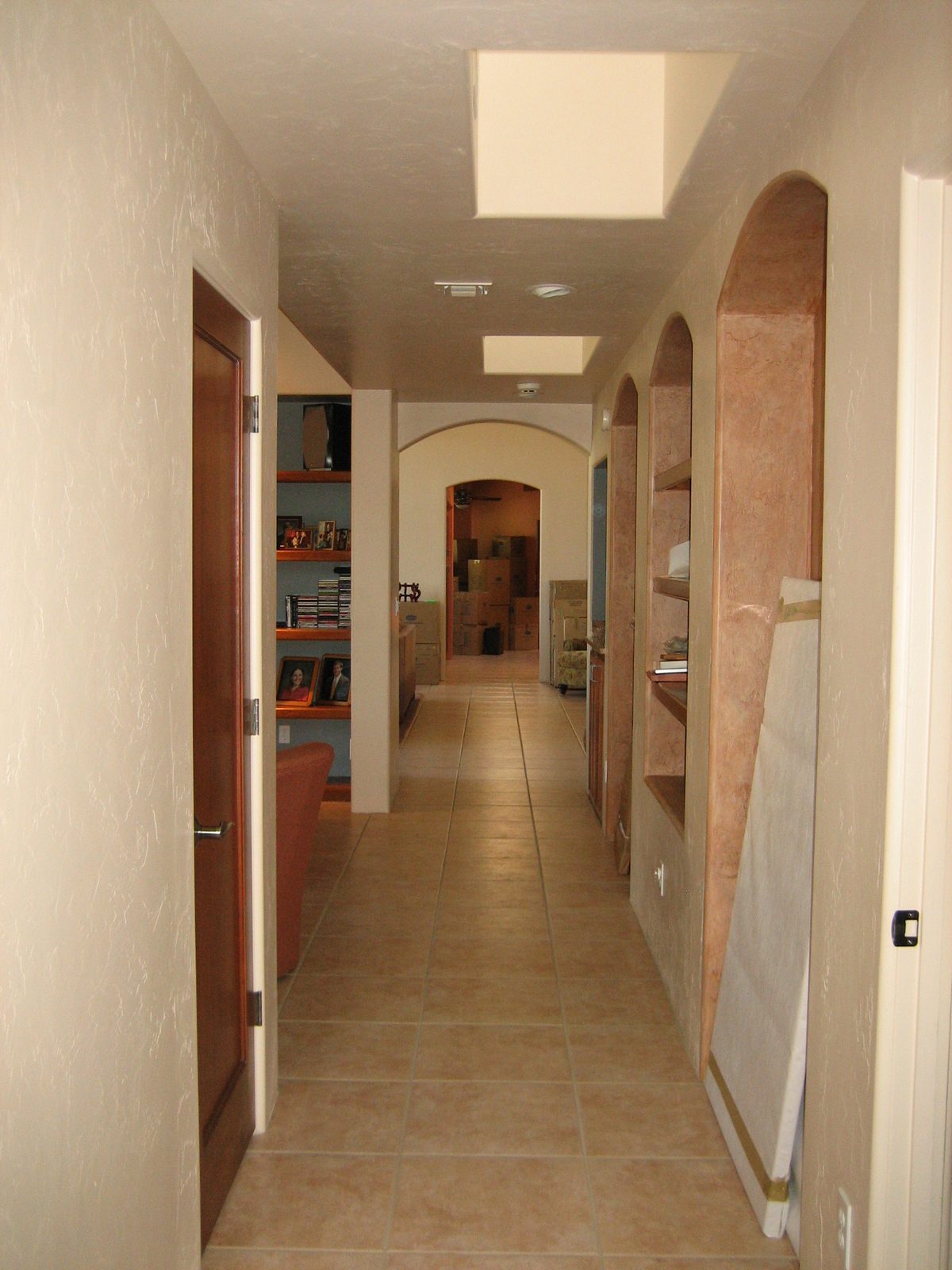 The long hallway from master bedroom (where photographer is standing) past the family room (with...