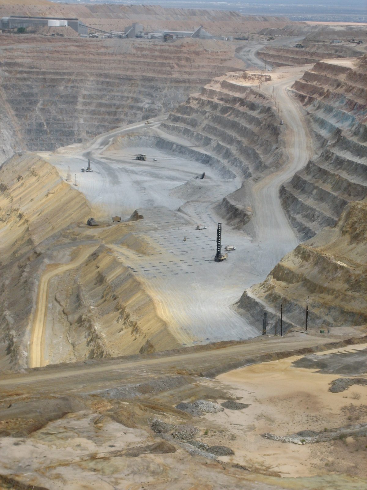 Mining operations.  The drill in the foreground is digging holes in which explosives are then...