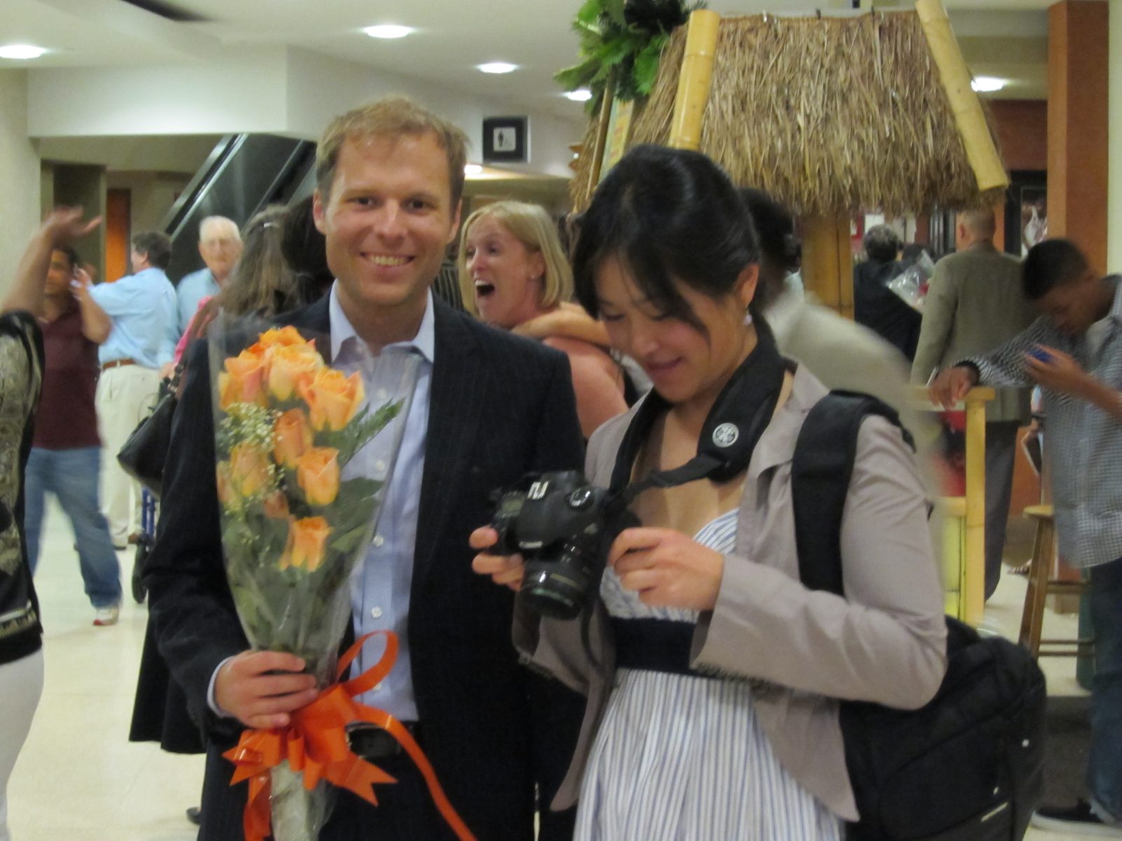 John carries flowers, Monica checks out a photo.
