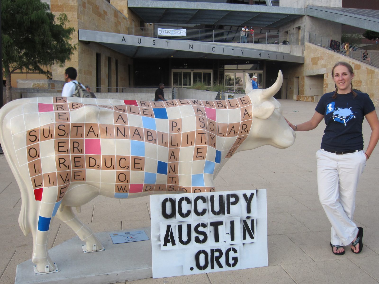 Catherine in downtown Austin, by a painted Scrabble-tile cow, and an Occupy Austin sign.  Just...