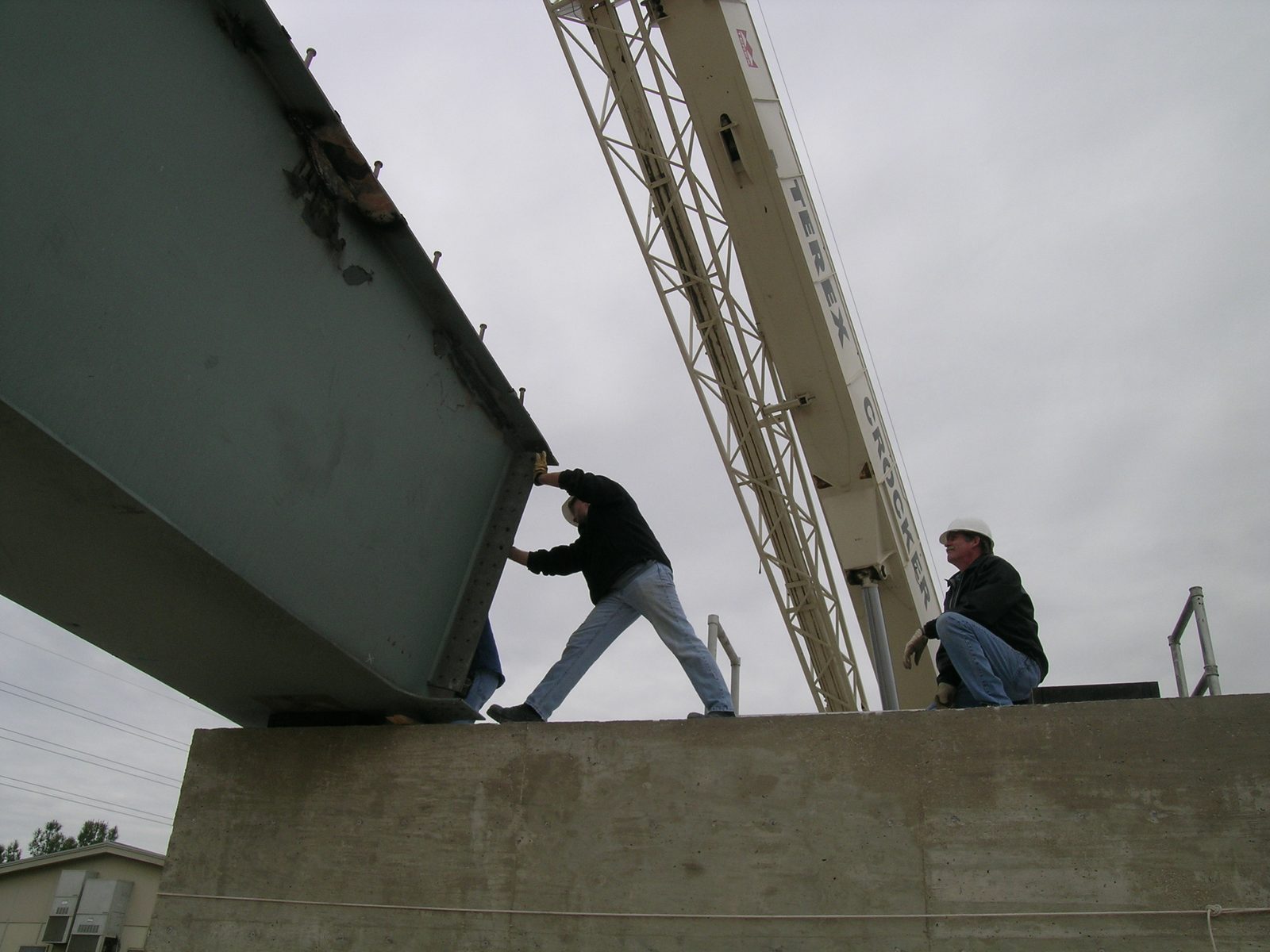 Tim pushes the girder into a more exact location; Dennis looks on.
