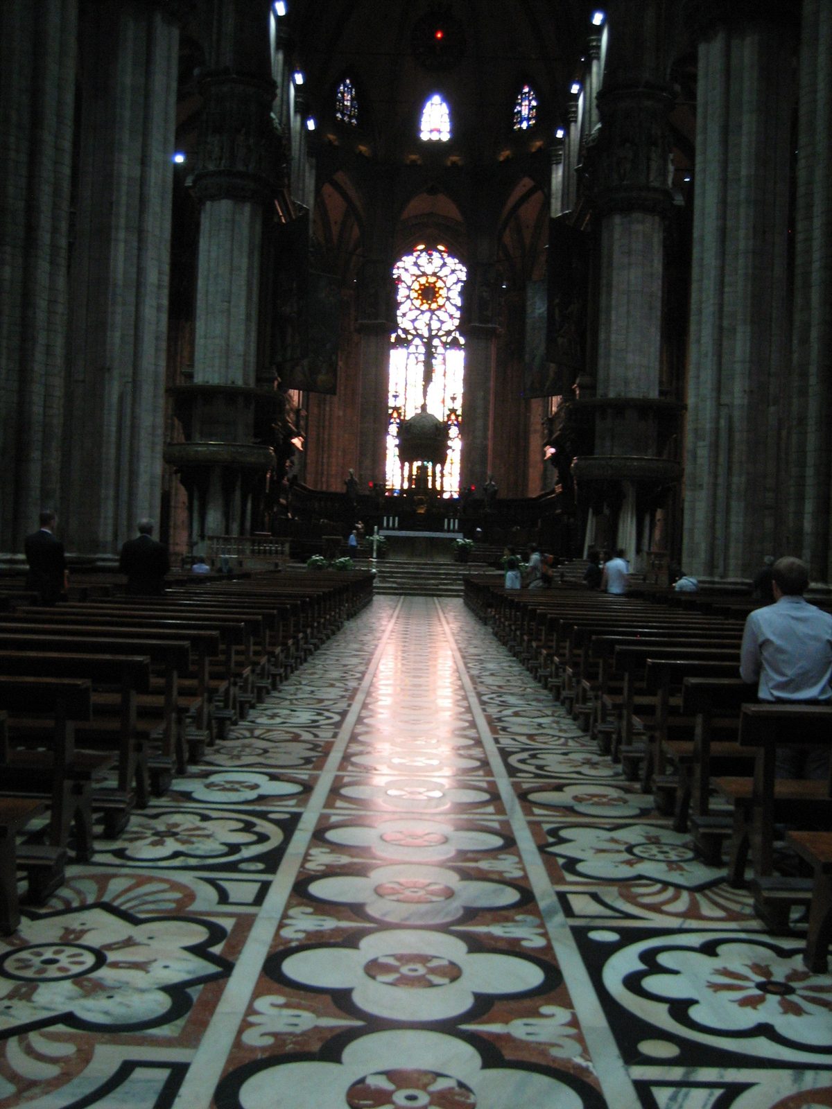 The main aisle in the Duomo, with the main stained glass window in the background.