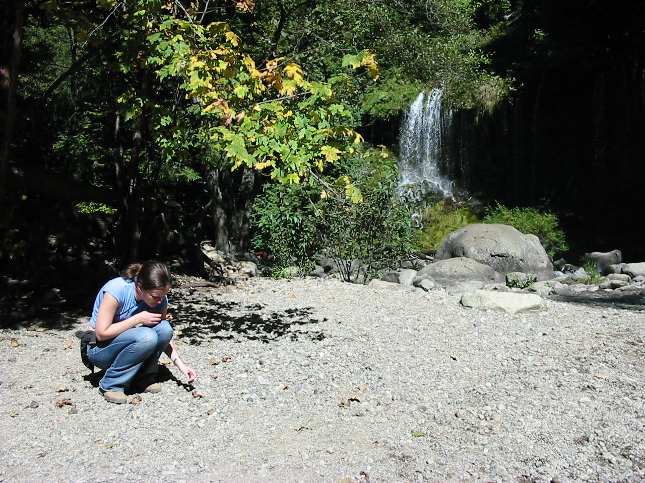 Rachel inspecting the river rocks near a basalt waterfall.
