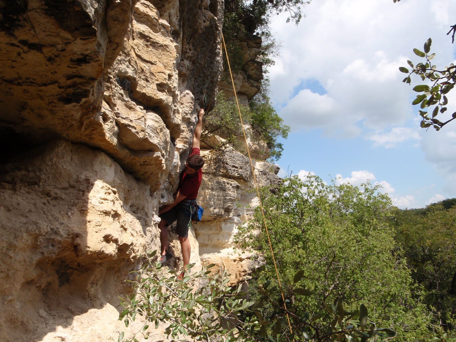 Jay making a bear's reach between a small finger jug handle and a sloping pocket.