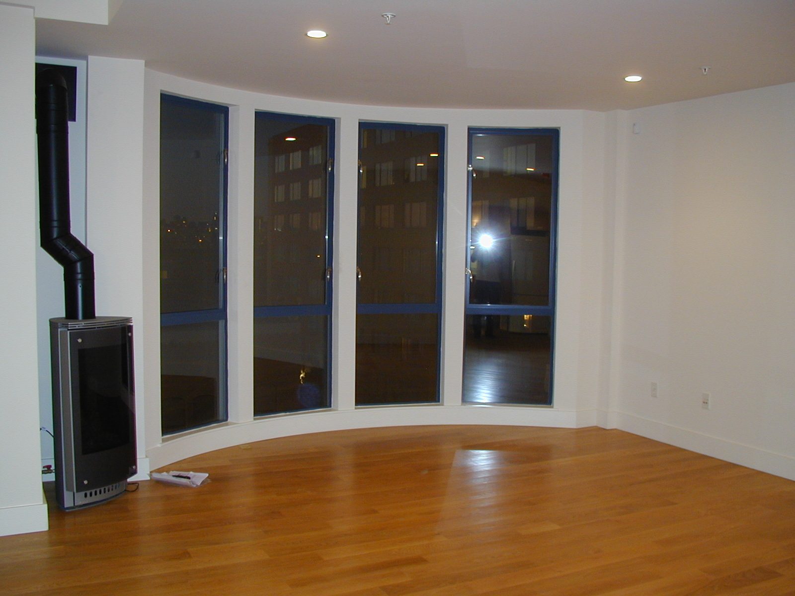 Living room as viewed from kitchen area.  Gas "fireplace" and bay windows facing north.