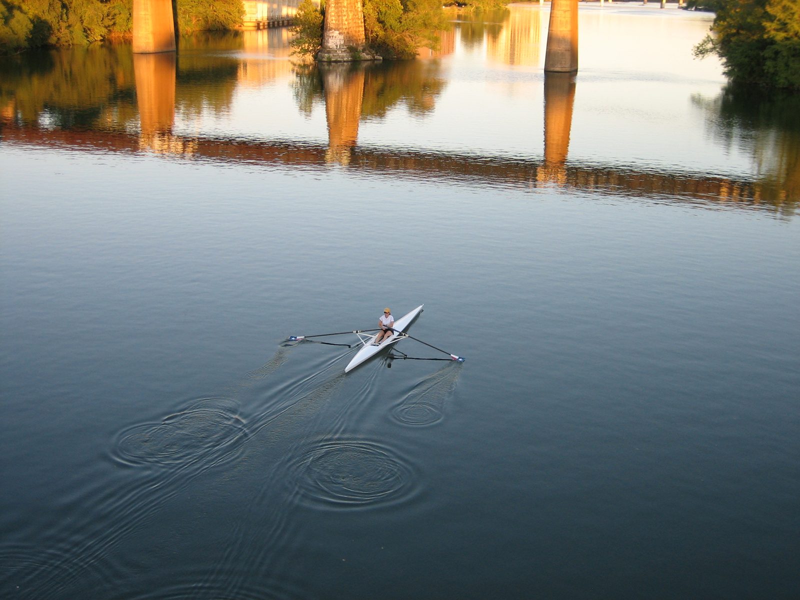 Skuller with Texas state flag oars on town lake.