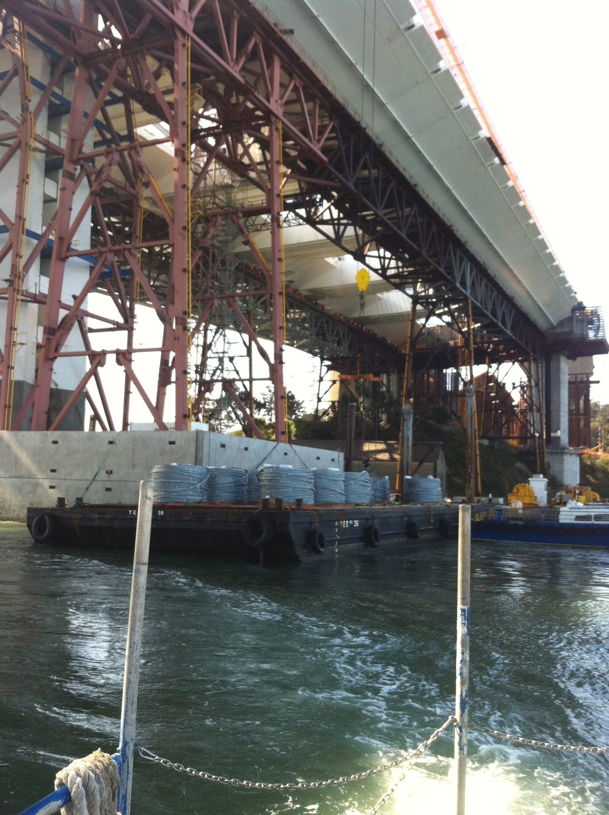 The silver spools on the barge are single bundles of steel cable used to anchor the ends of the...