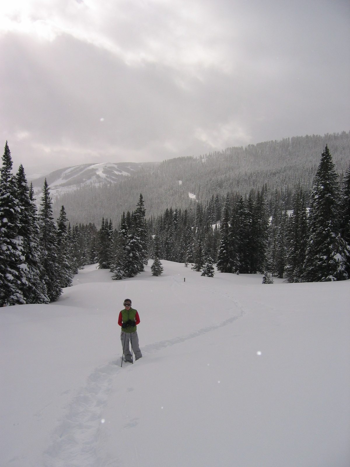 Rachel on the trail, with snow falling over the Lone Peak area in the background.