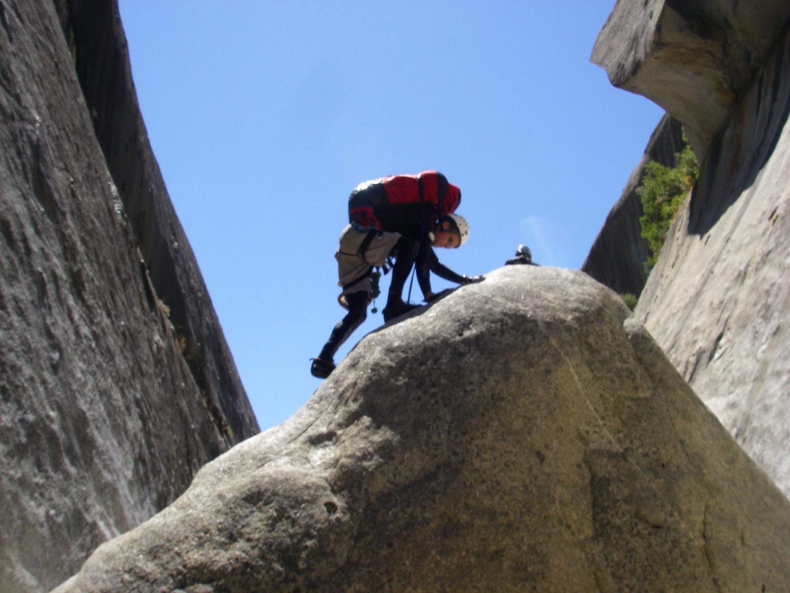 John climbing a boulder to find a rappel bolt.
