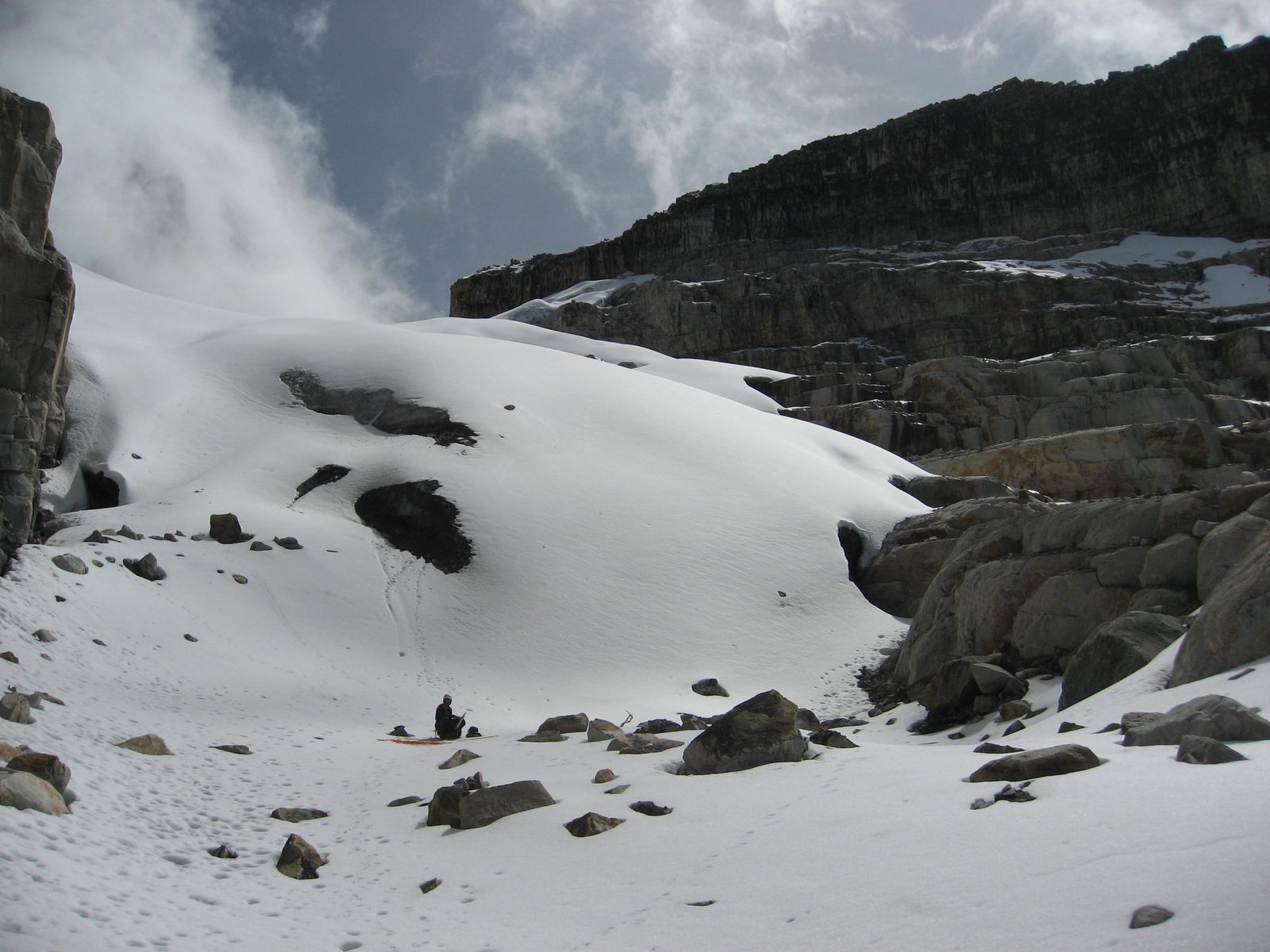 The beginning of glacier. Rodrigo sits down for a snack, and dons his crampons, rope, etc.