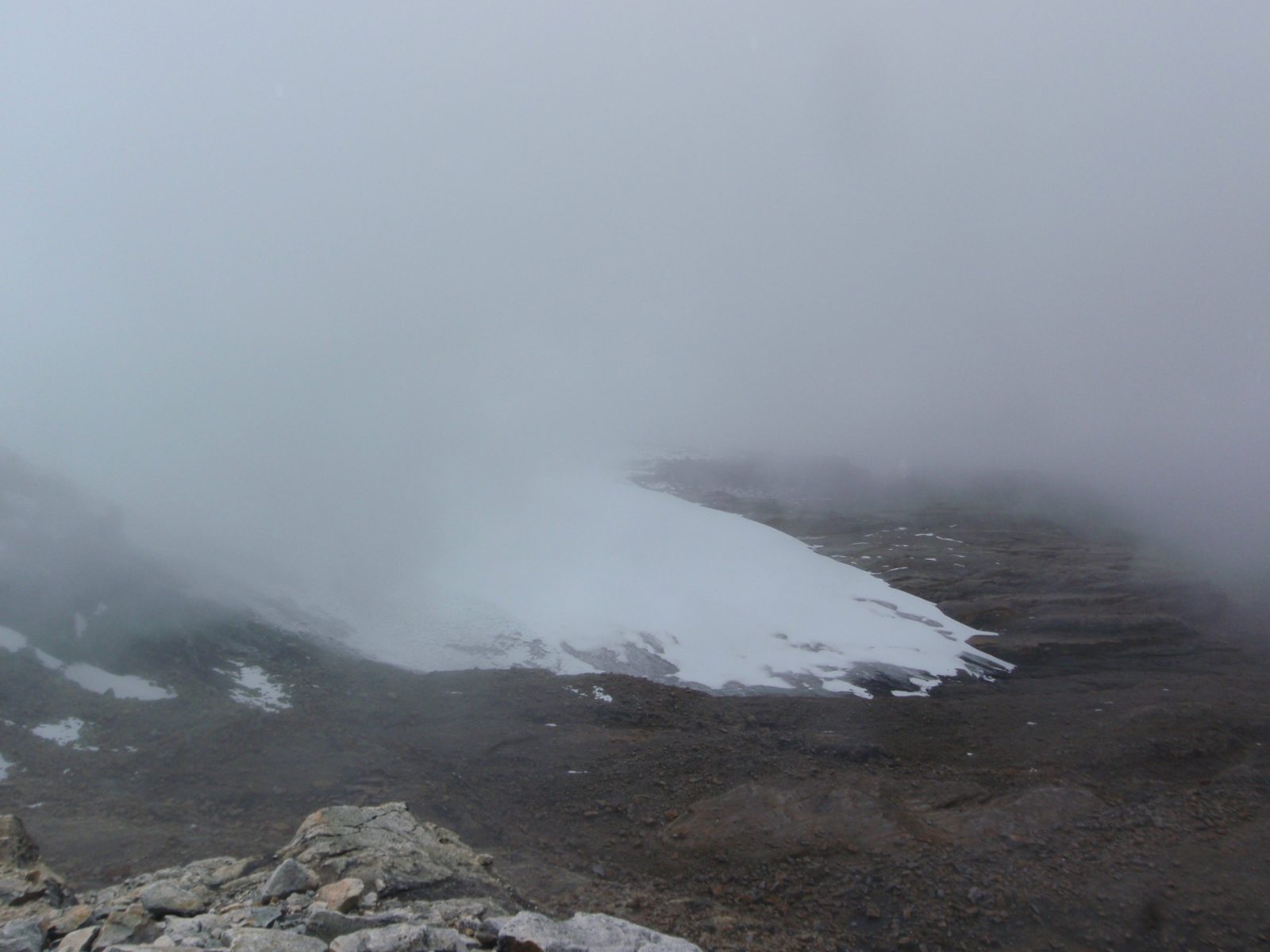 The toe of the glacier, mostly wrapped in fog.