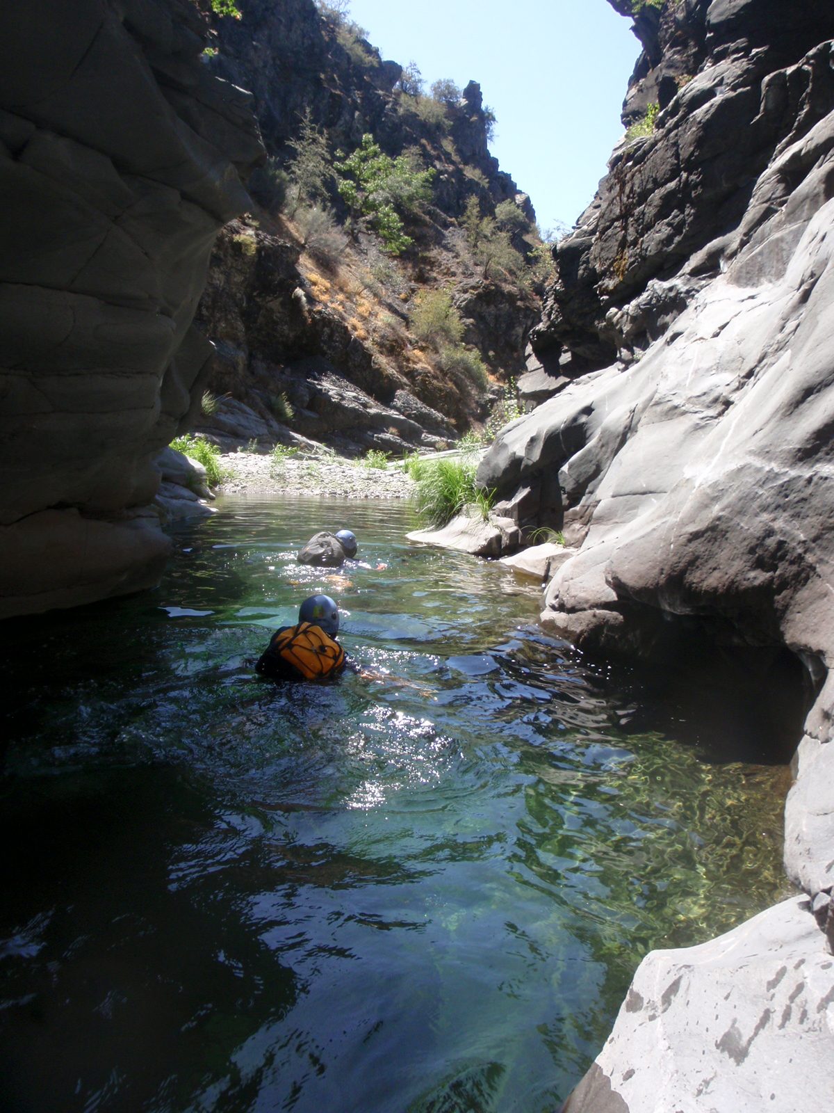Monica and Christina, suspended with backpacks like buoyant turtle shells, paddle across a small pool.