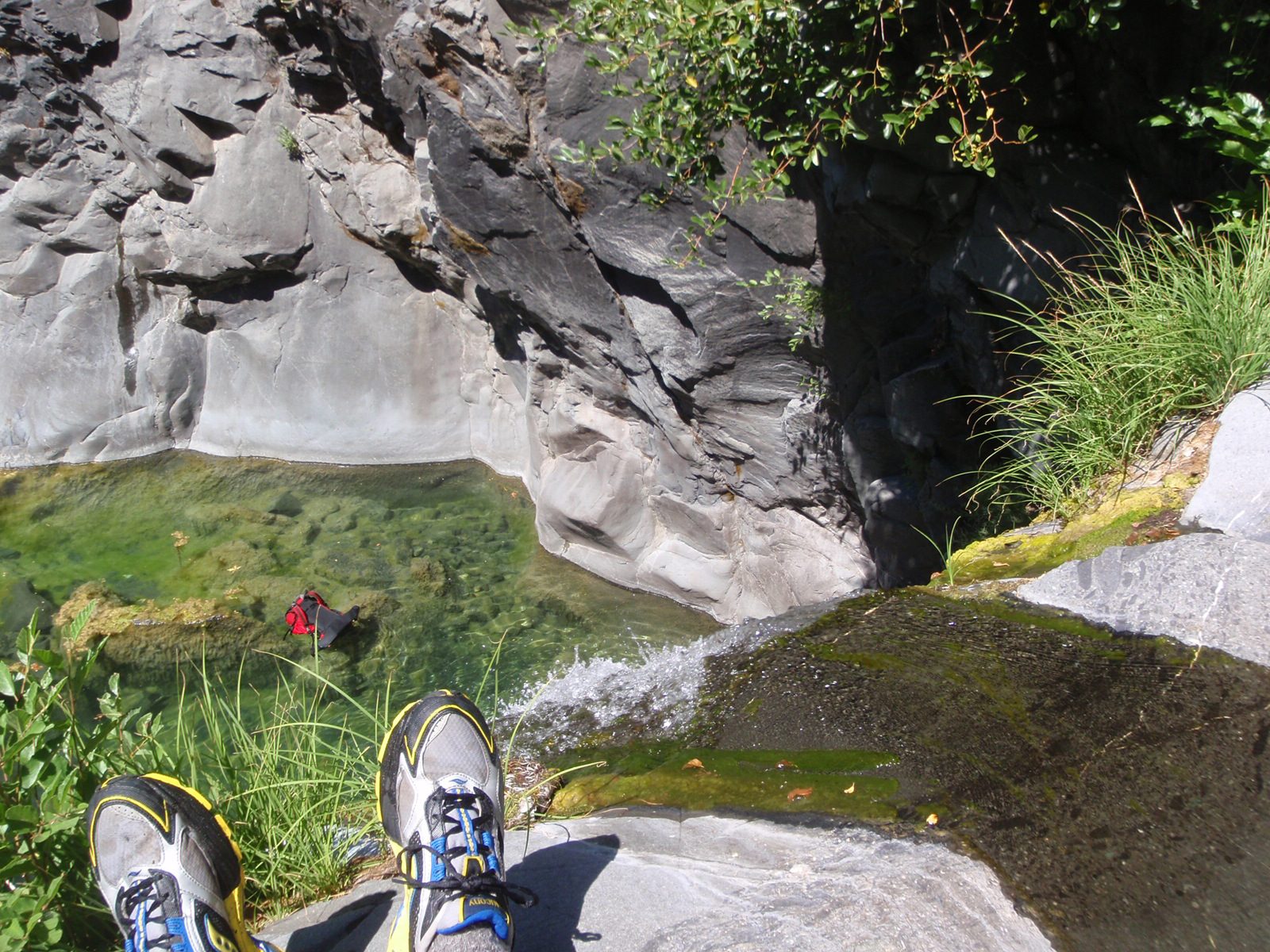 Chris's feet dangle over the edge of the first rappel.