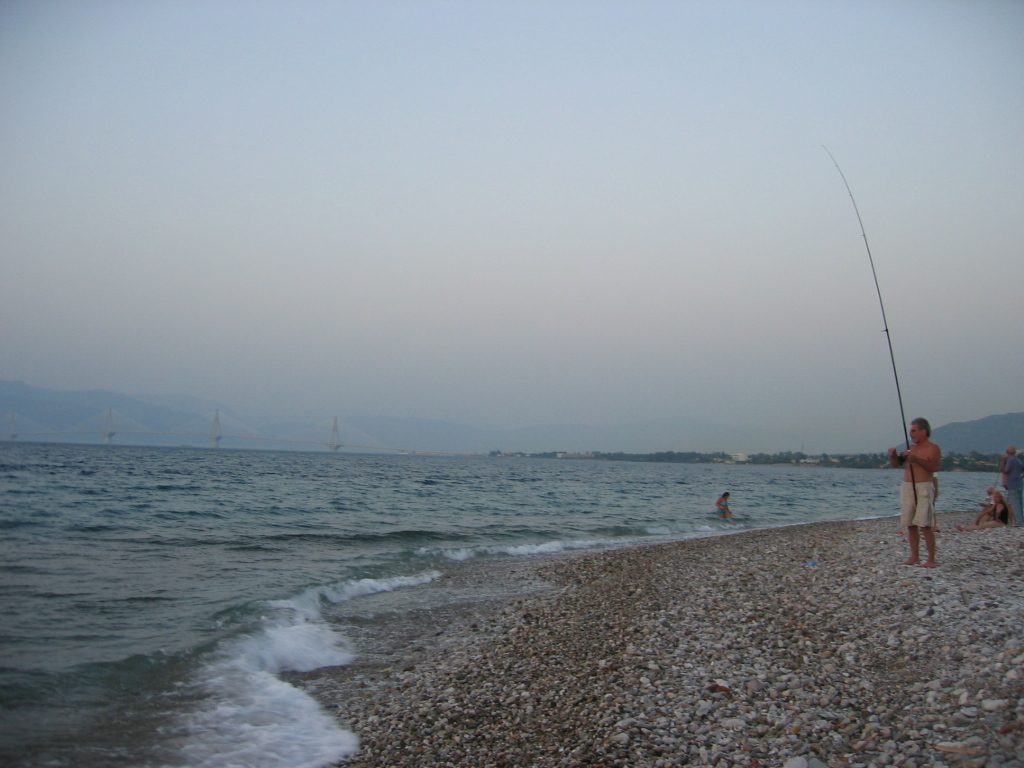 Some fisherman dude with the Rion-Antirion bridge in the background.  It was so warm and the...