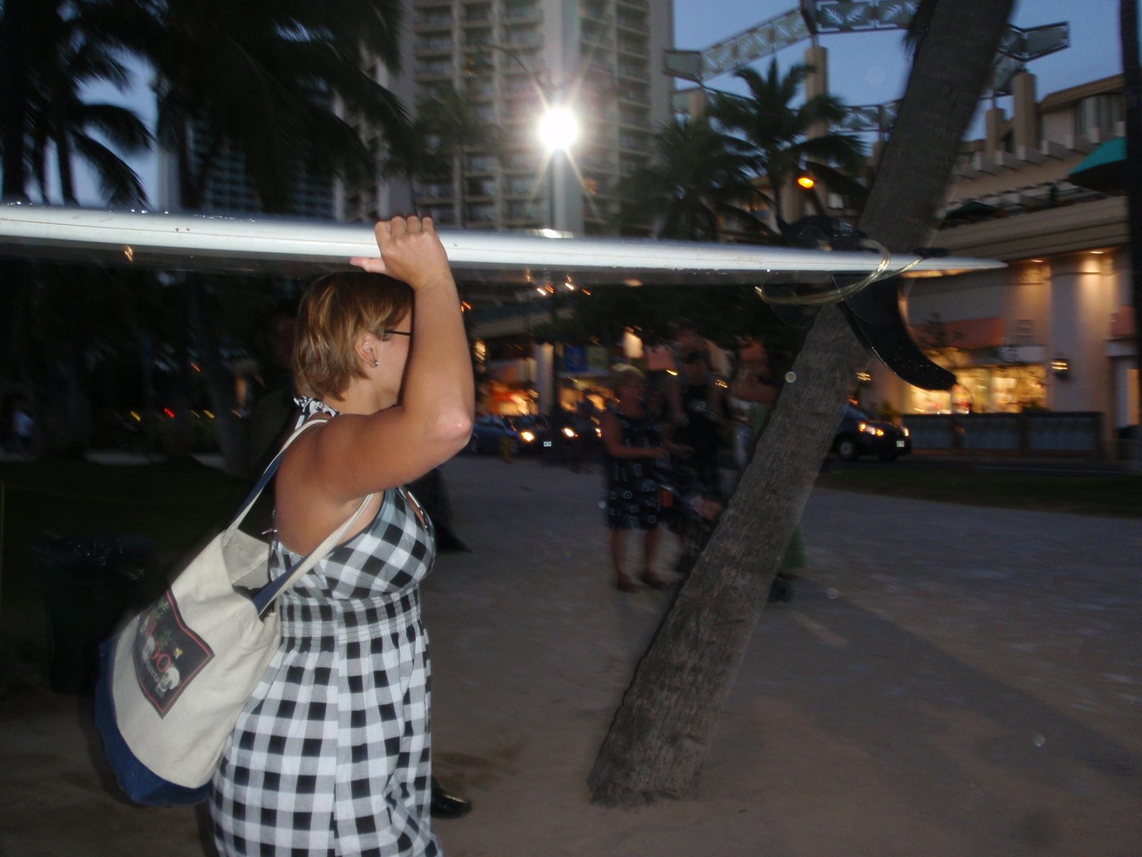 Lydia carrying her surfboard back to her moped.