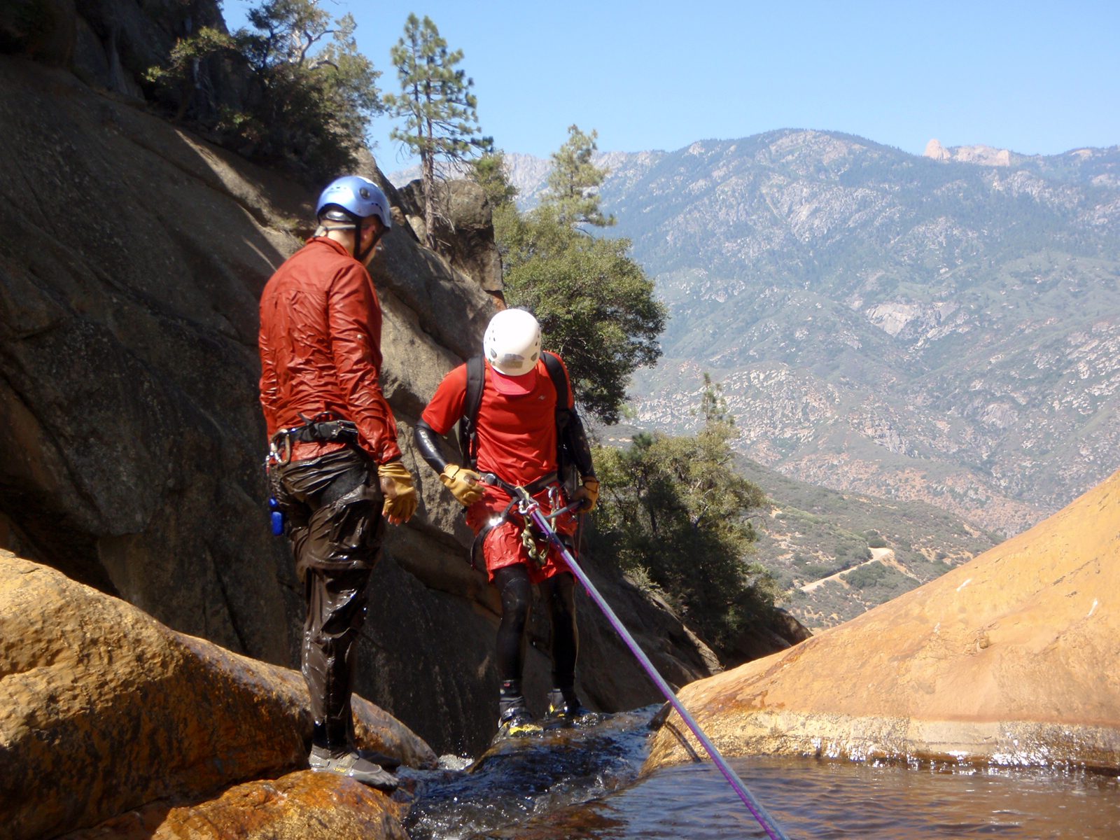 John starting the third rappel, while Joel double-checks rigging.