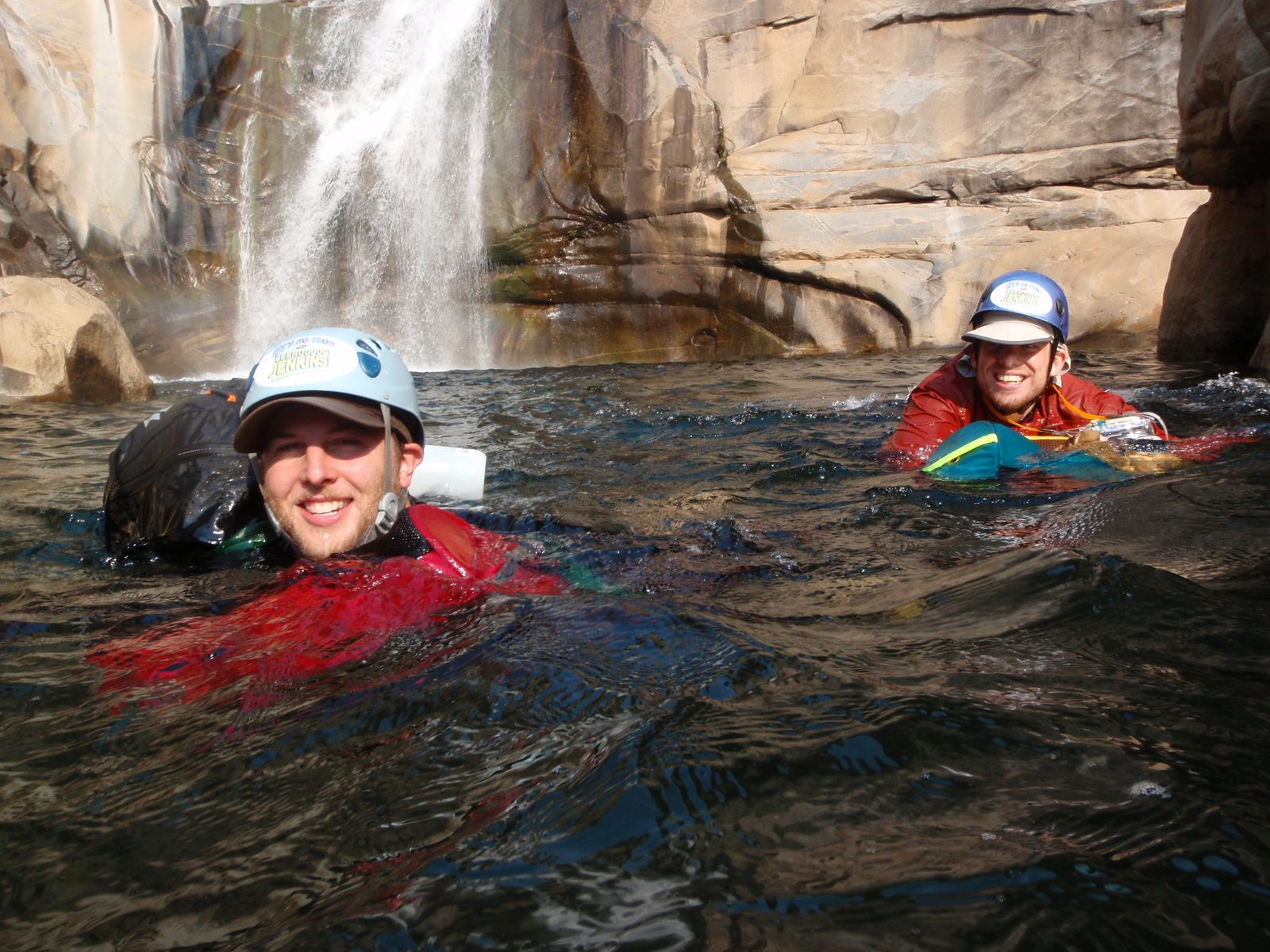 Mike and Joel paddling down river with bags (bottom of the 150 ft waterfall in the background).