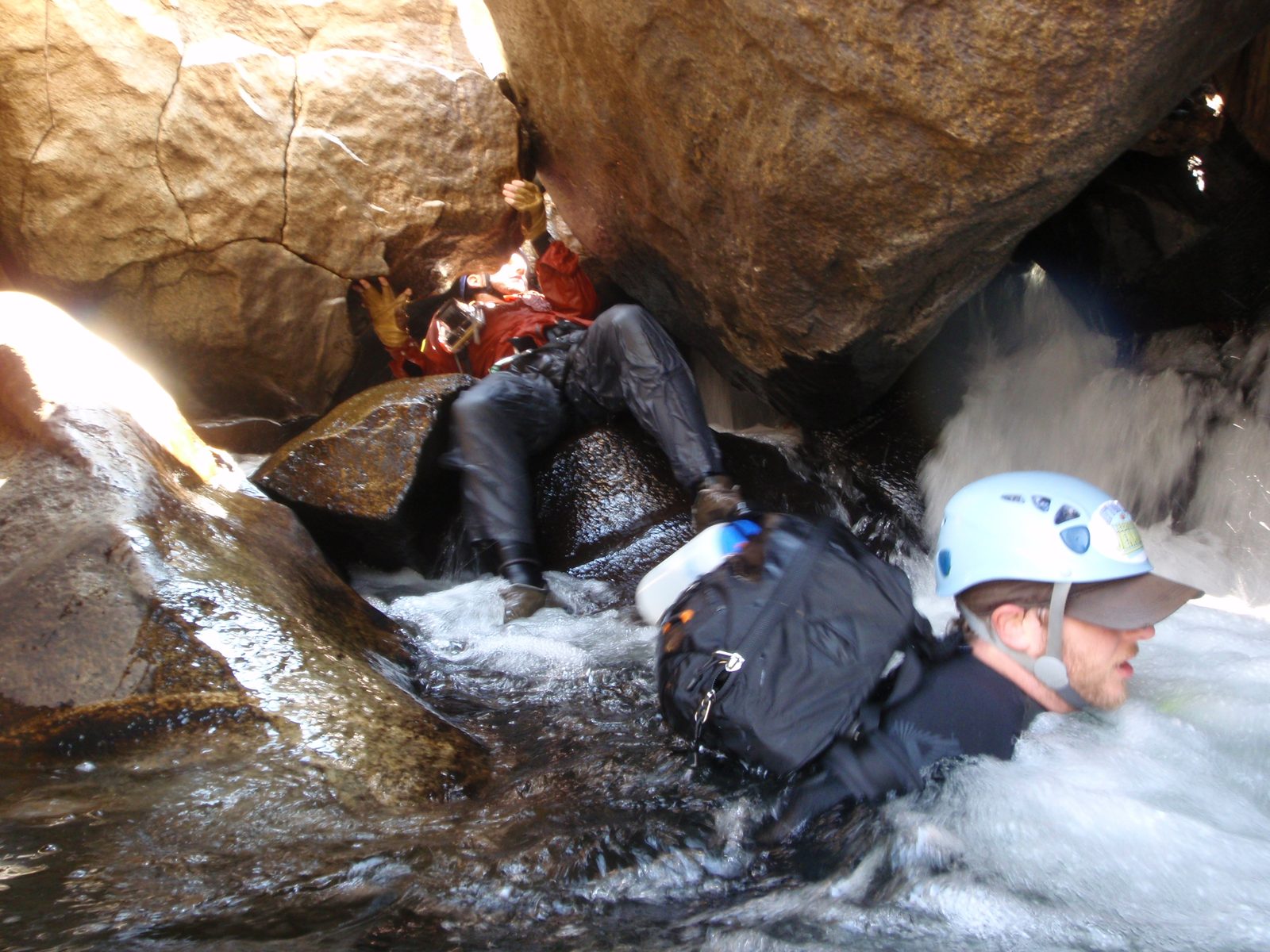 Joel coming through an opening between two massive boulders, as Mike swims out of the current below.