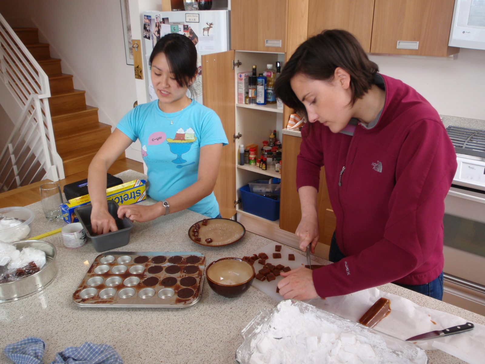Monica eats while Kaitlin makes.  (Completed marshmallows at lower right.)