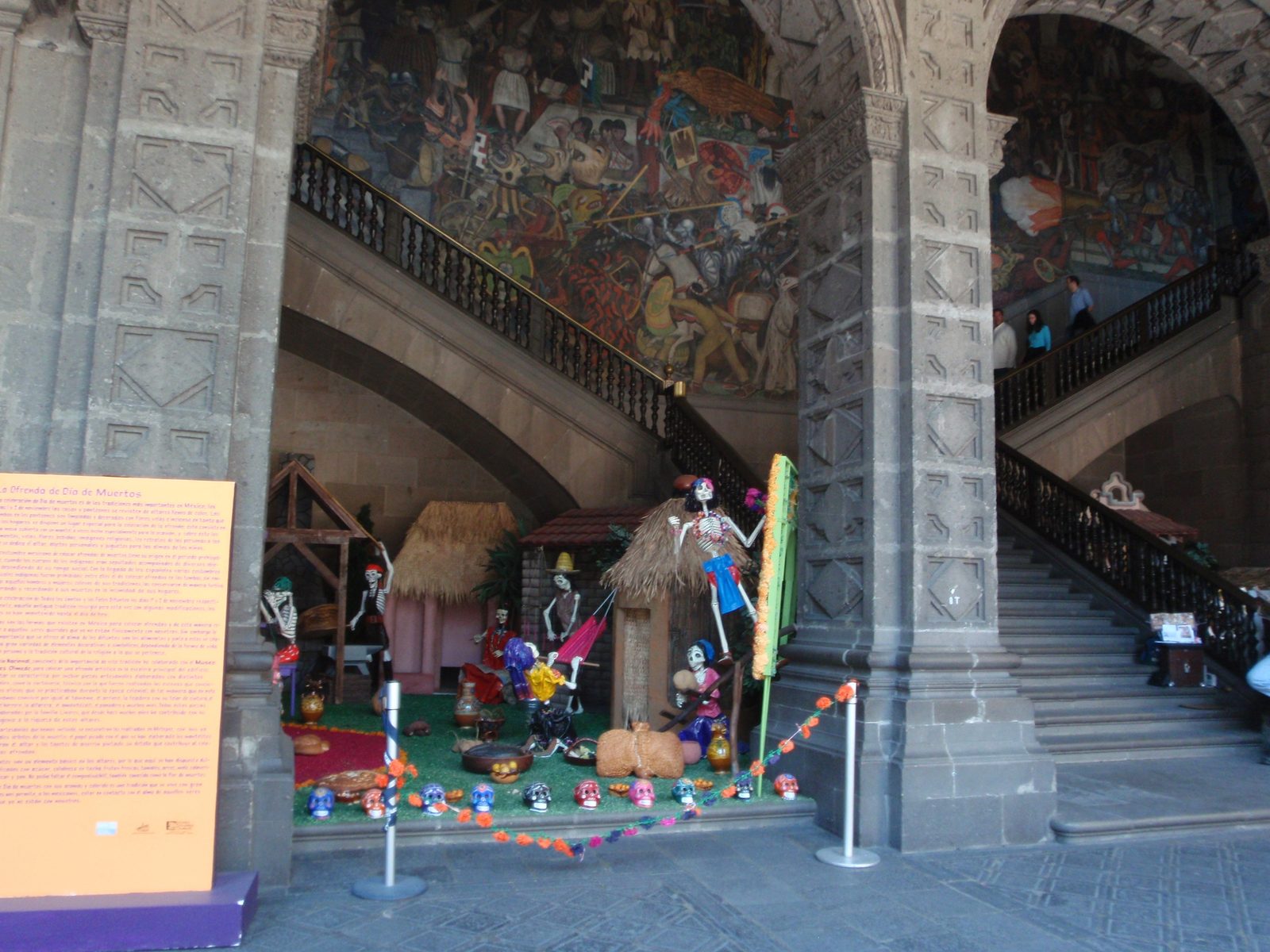 Dia de los muertos display and Diego Rivera mural in the background.