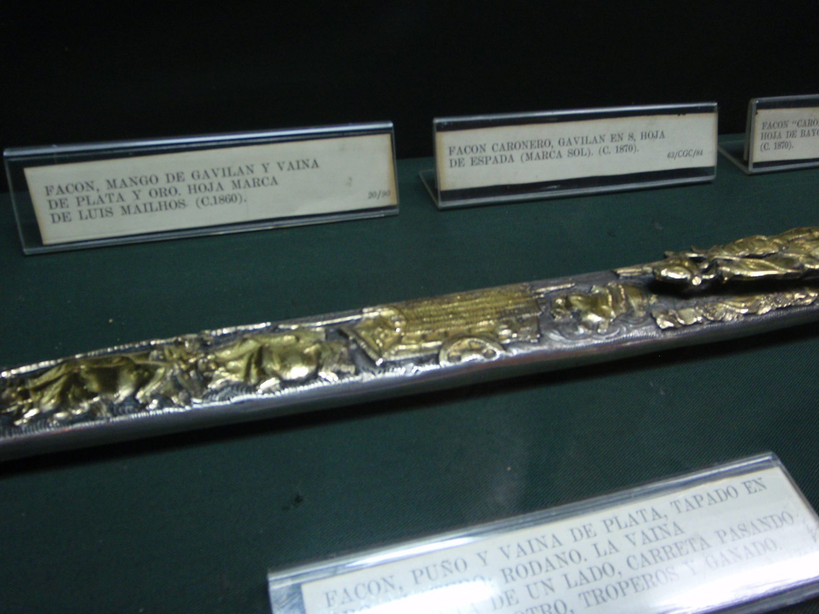 Sword sheath.  Plata y oro means silver and gold.