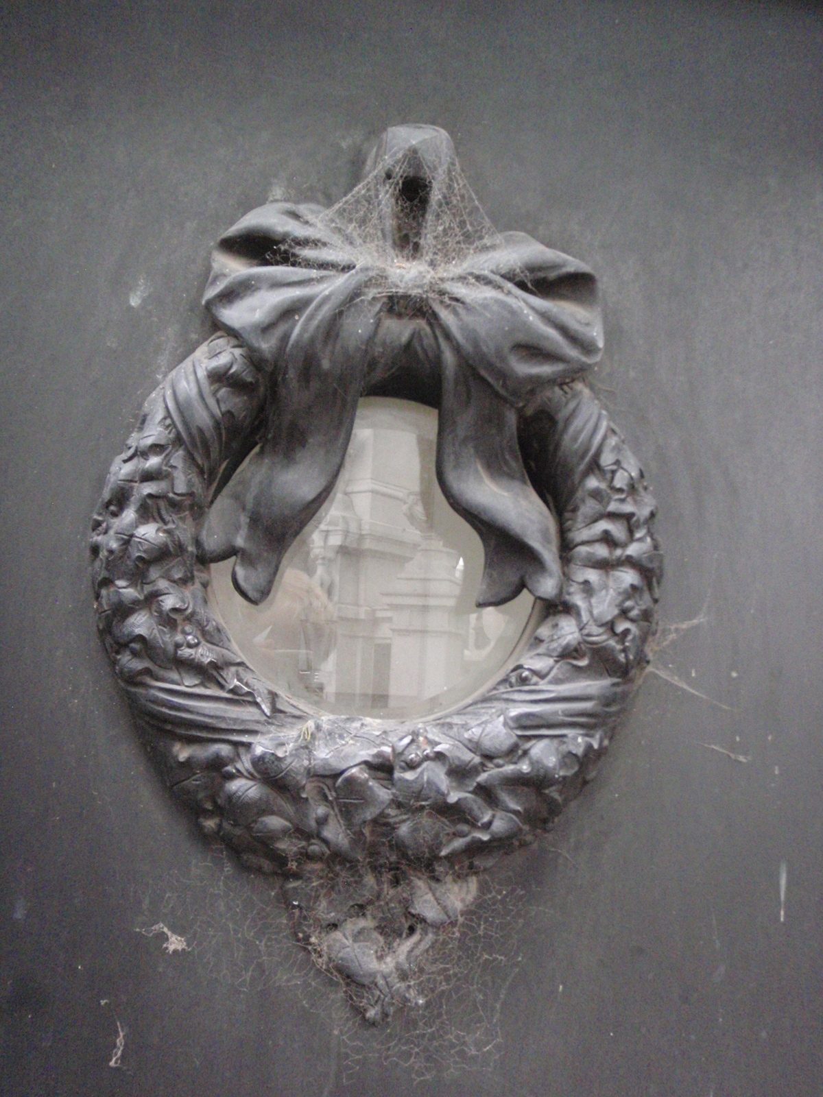 Creepy glass window covered with cobwebs on the front door of a mausoleum.