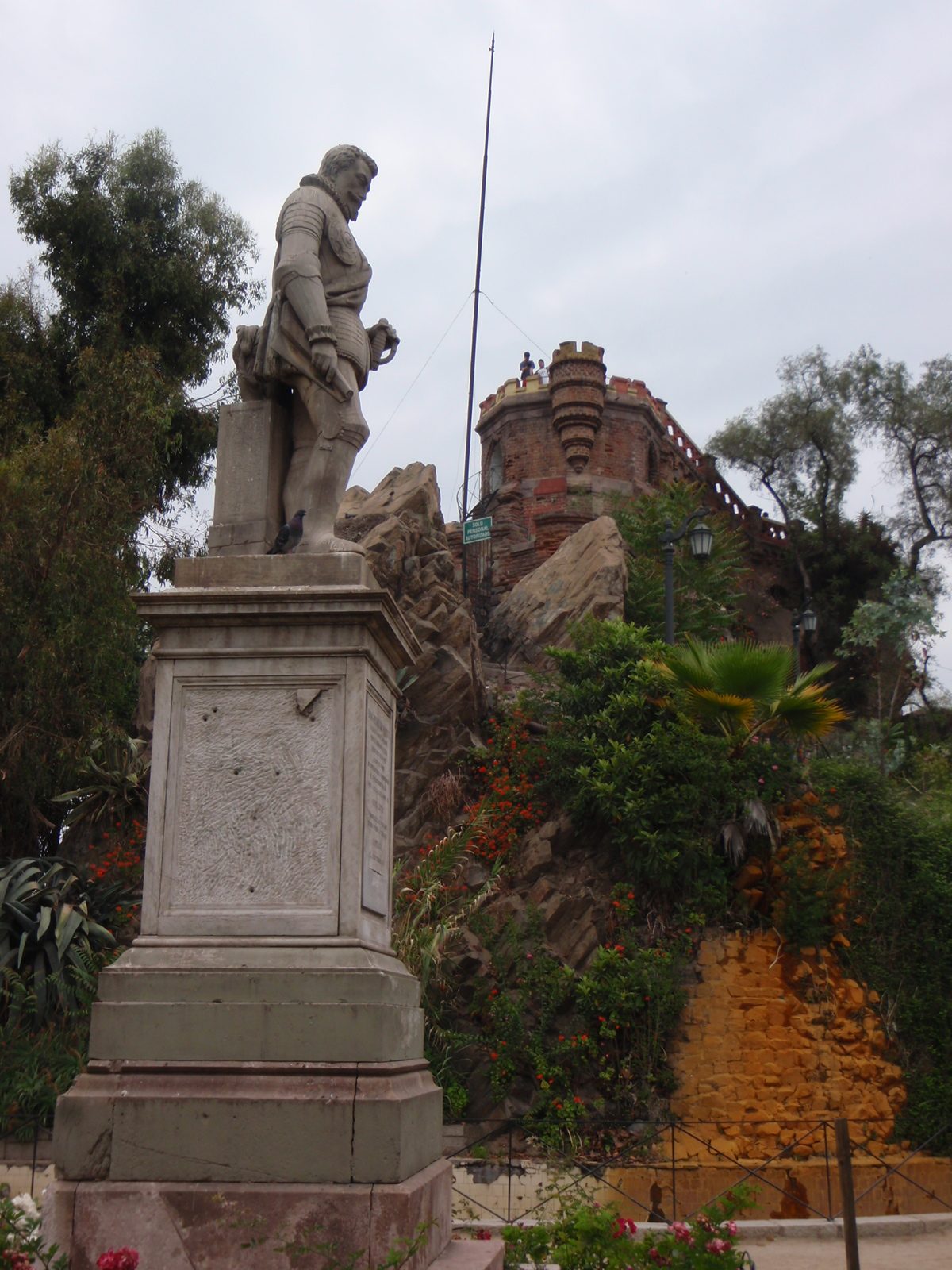A statue of some guy, with a castle in the back.
