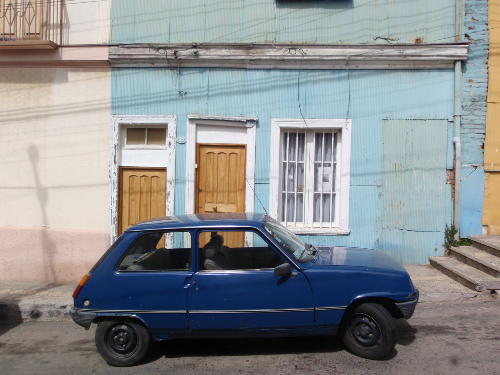 Funky corrugated metal house with a blue car.
