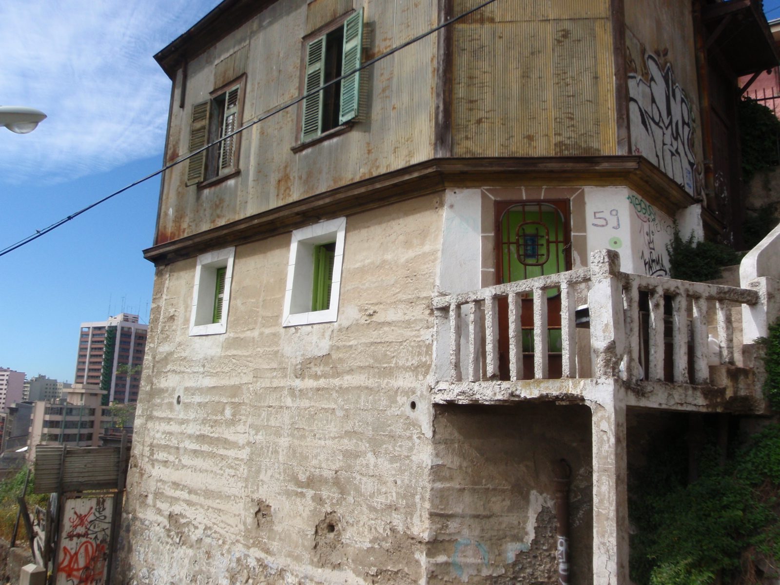 Old house with graffiti and crumbling foundation.
