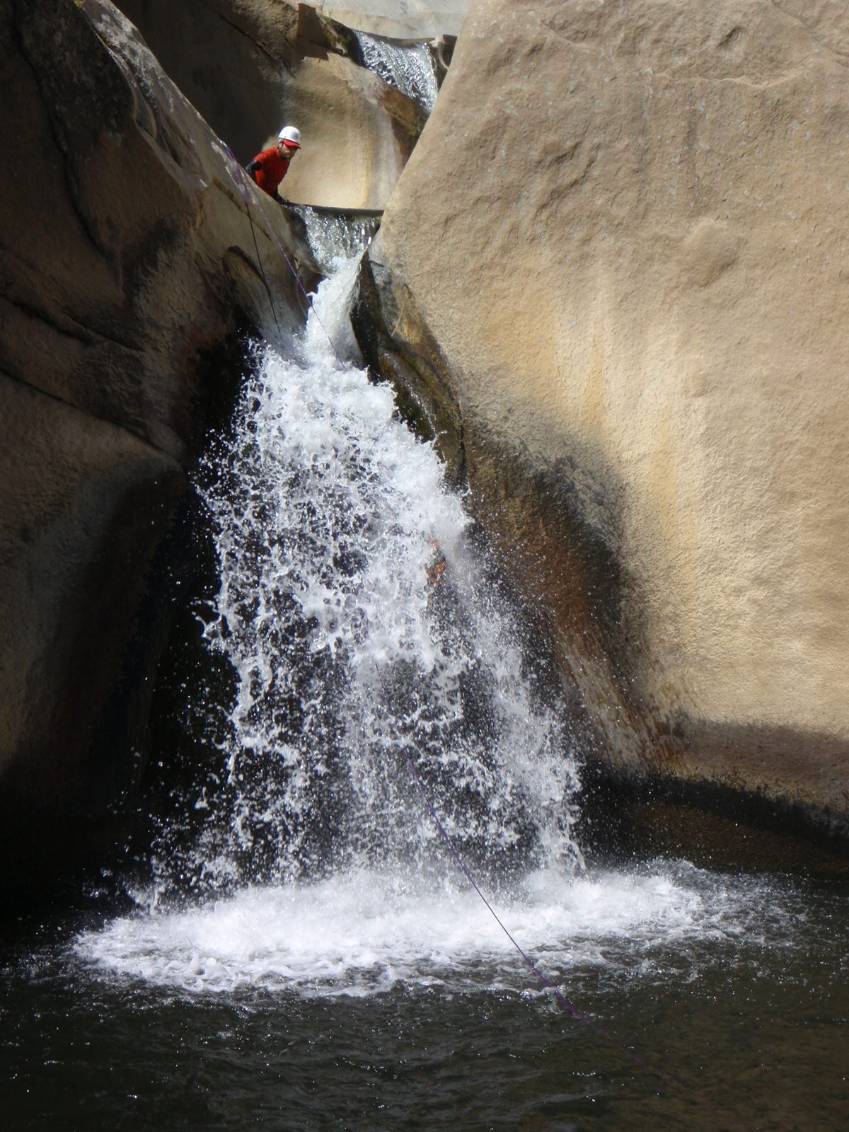 Monica, inside a waterfall.  John looks from above.