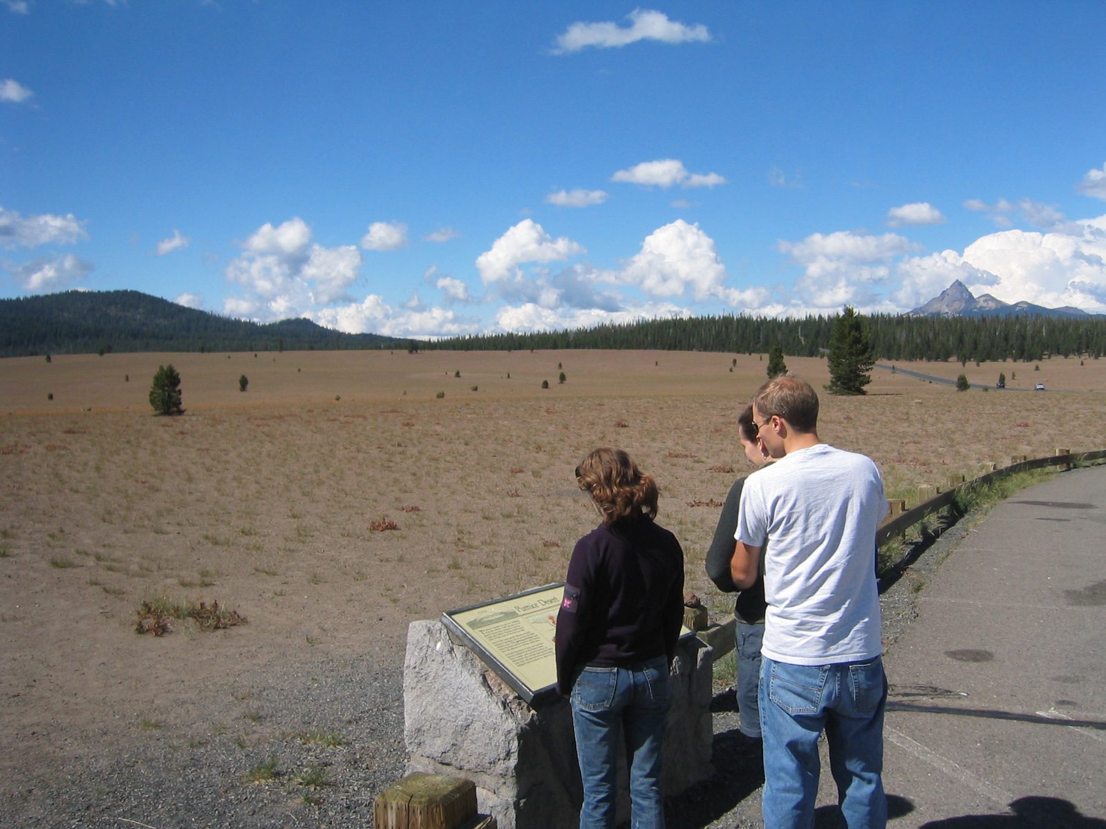 Alison and John (Rachel obscured) reading an "interpretive panel" in the middle of a volcanic...