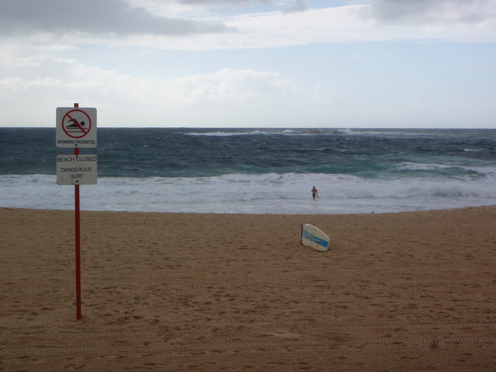 Swimming Prohibited.  Beach Closed. Swimmer swimming.  Such is Australia.  Signs everywhere...