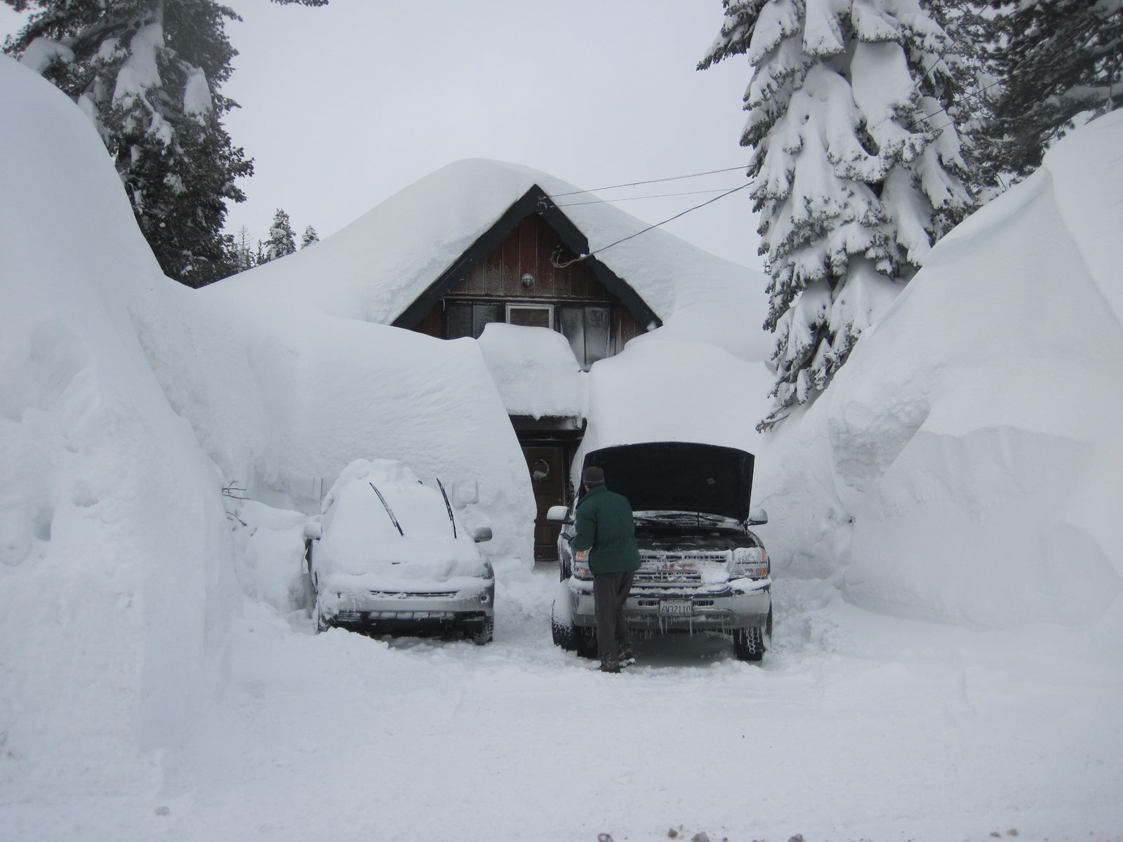 Most two story houses were completely covered in snow. Here a man whose house is relatively...
