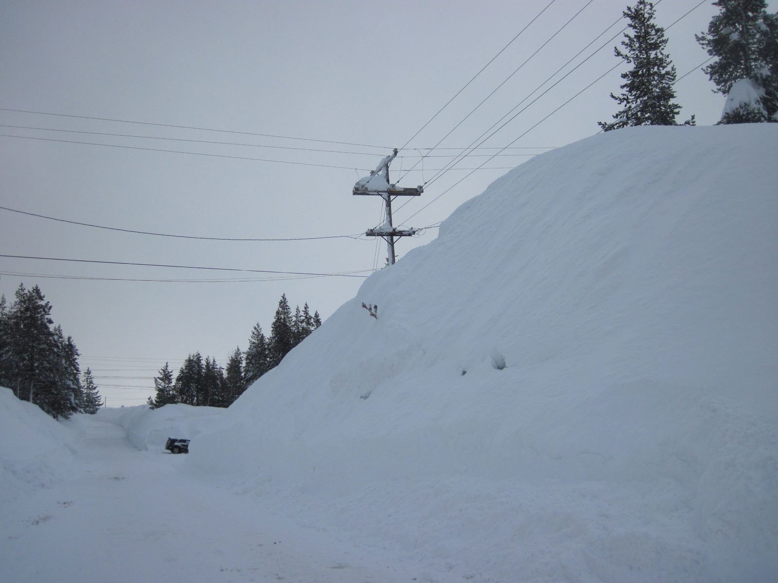 Snowbank that is higher than the electrical wires running down the street.