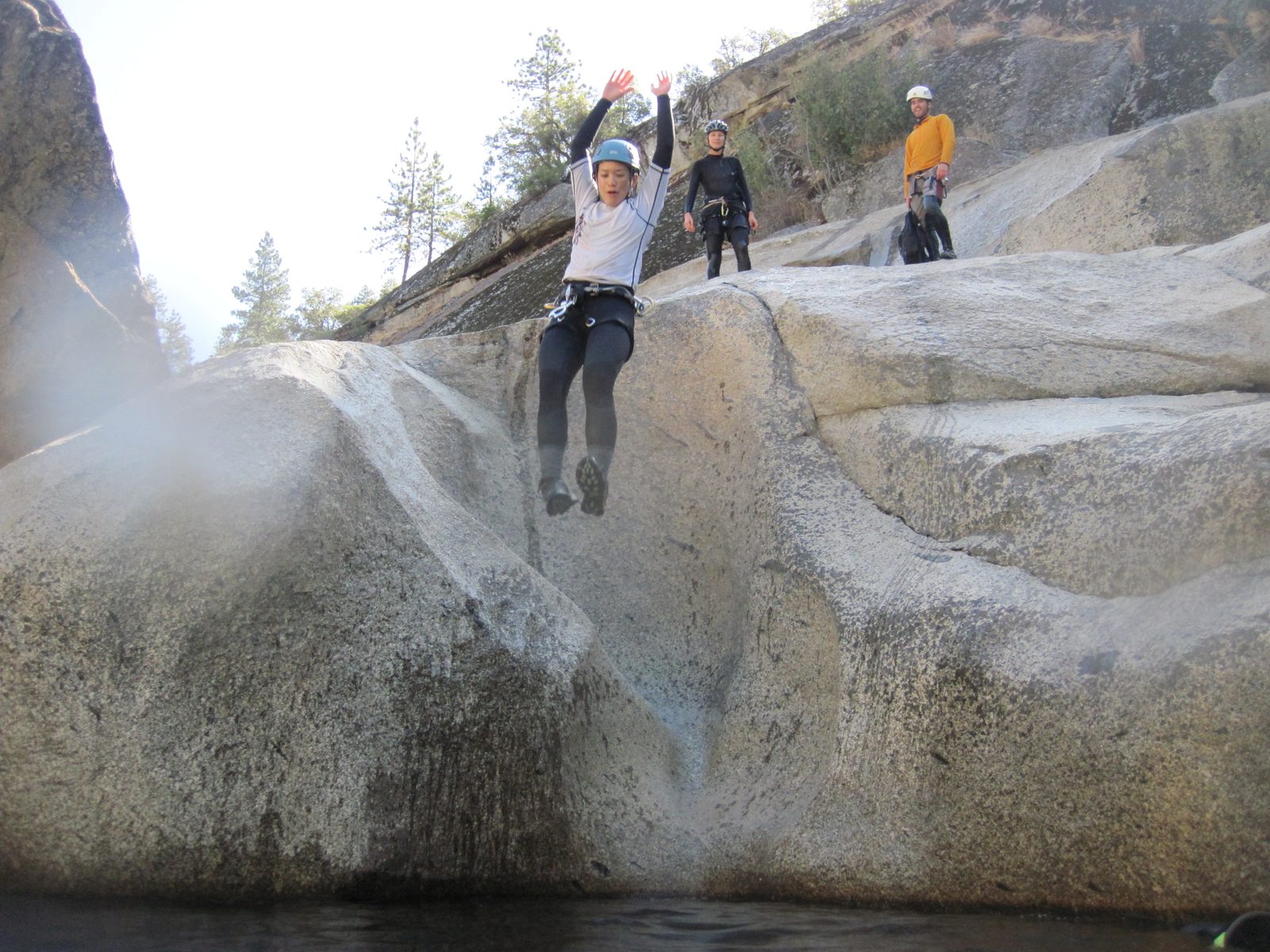 Tracy jumping in the water. Julia and Eliah look on from the background.