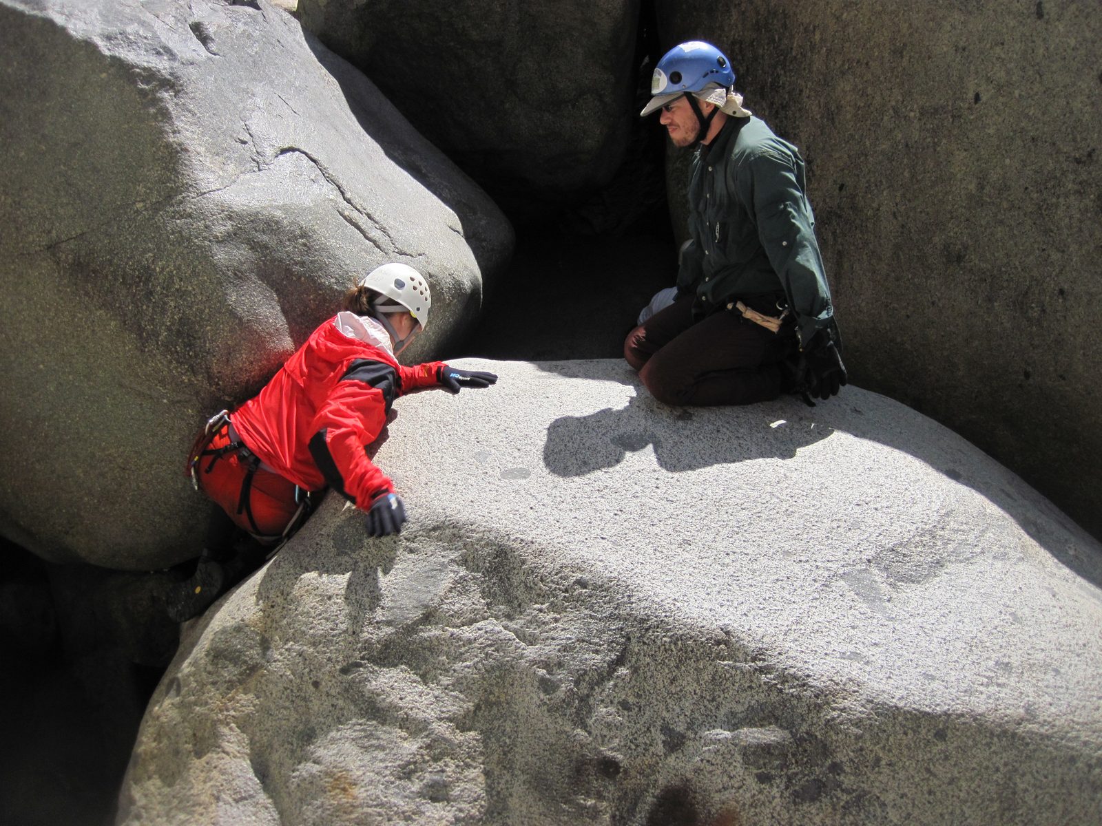 Joel watching as Jill climbs up a boulder to enter a cavernous section of the river (black hole...