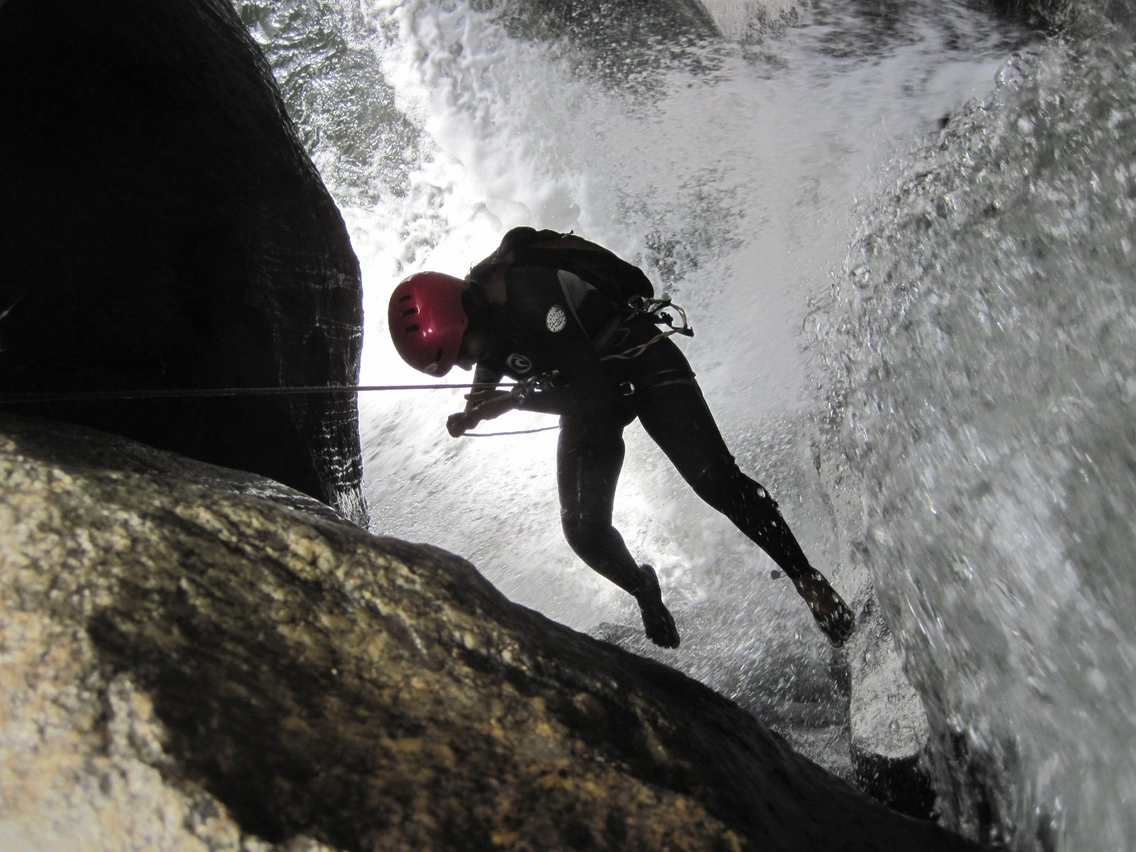 Aditi rappelling into the waterfall, wearing Vibram Five Fingers.