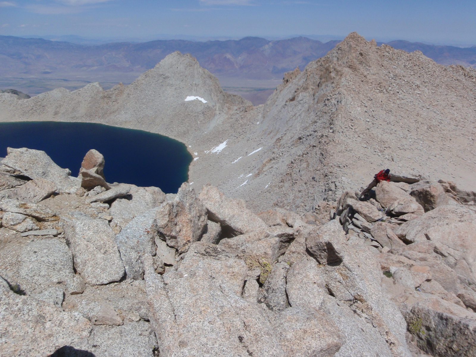 Joel climbs up over some rocks on the East Ridge of Russell.  The flat land in the background is...