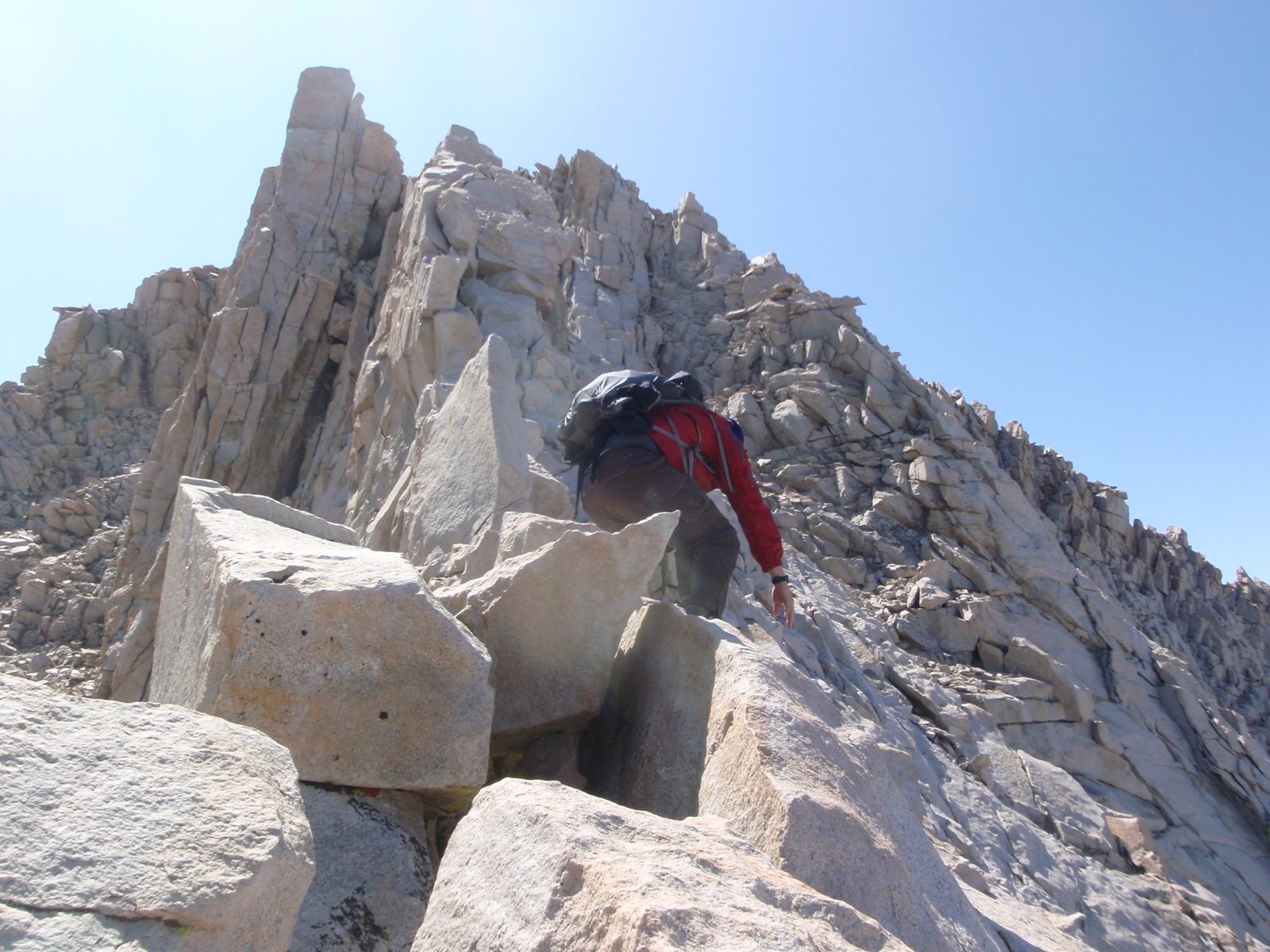 Joel, scrambling up the East Ridge as it starts to get narrower: on the right the mountain falls...