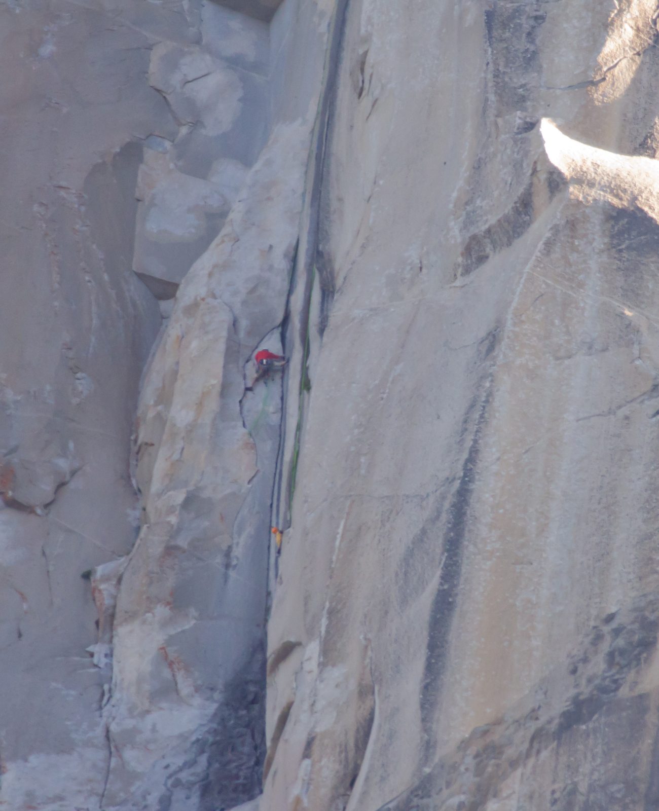 A photographer hanging from an identical green rope (with orange helmet) photographs Hans as he...