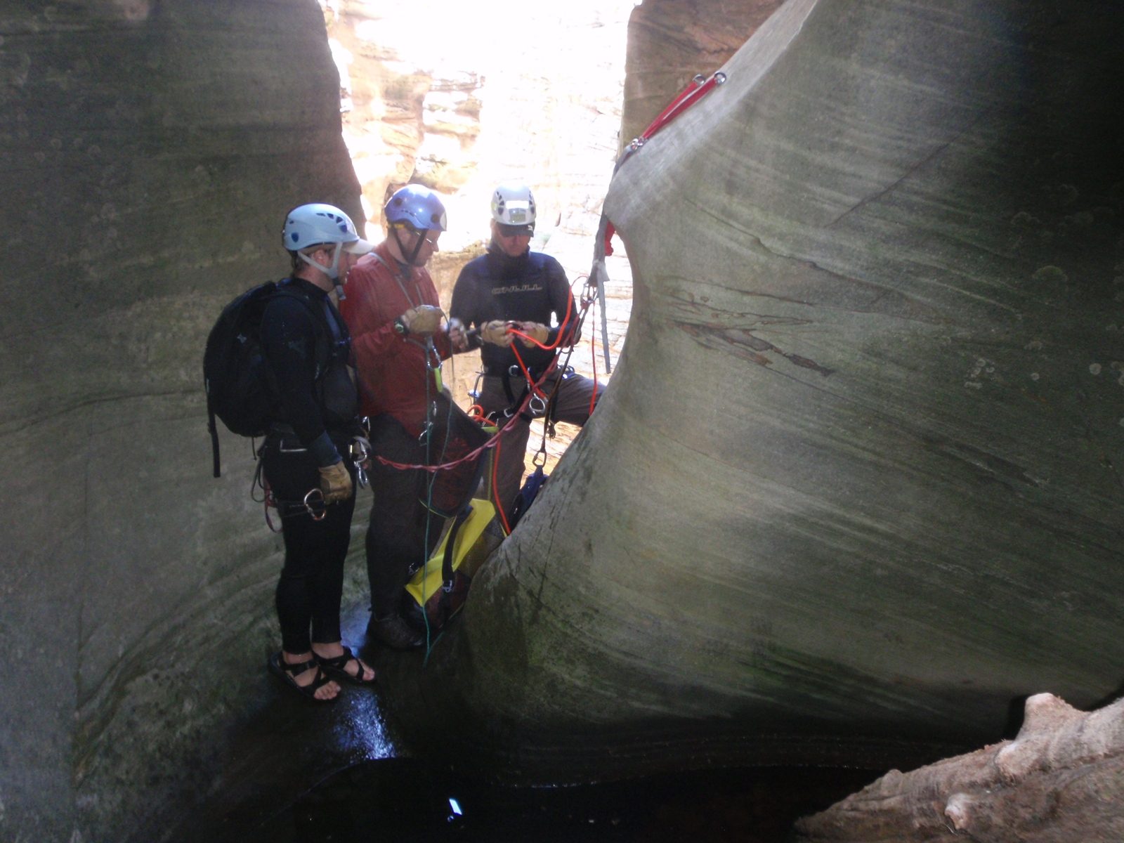 Mike, Joel and Andy carefully inspect the rigging of our final 170 foot rappel, 130 of which...