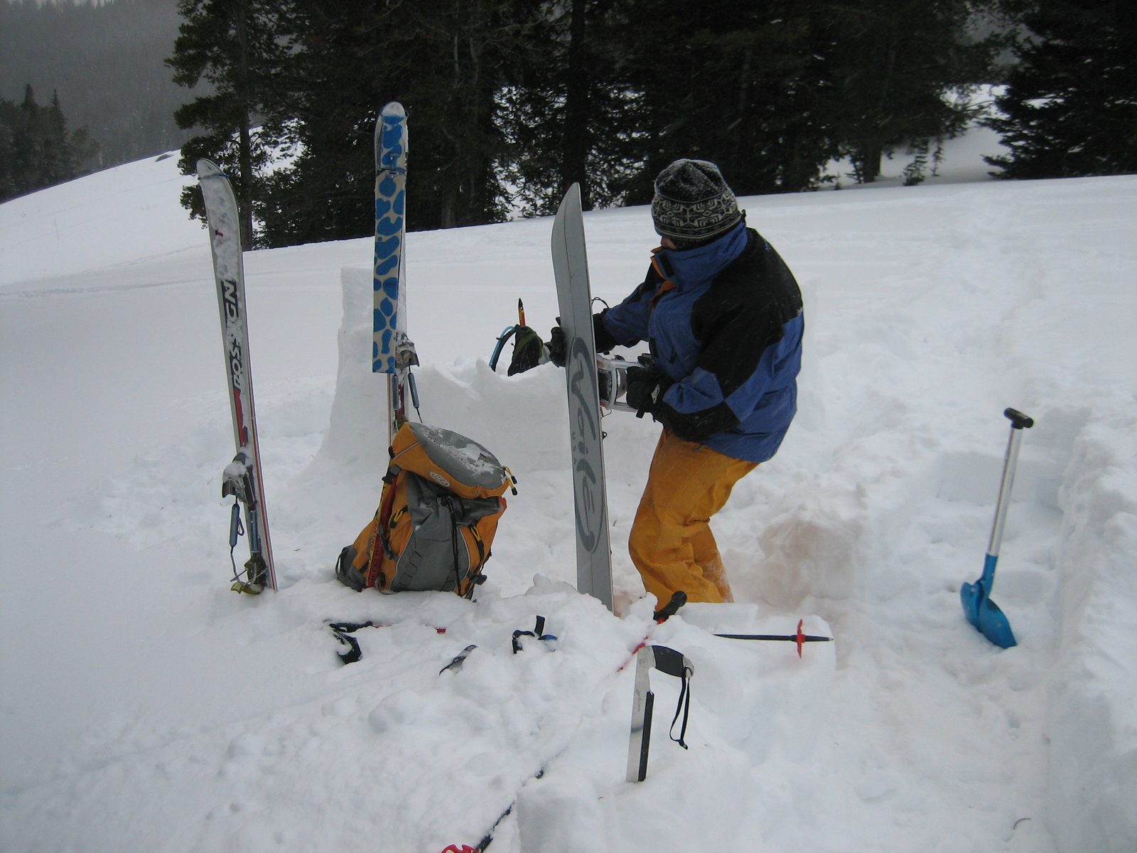Catherine, putting her split board in downhill mode.  Snow brick quarry in foreground; igloo in...
