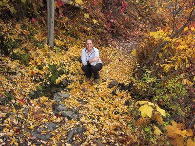 Catherine poses in a bed of leaves near a cross-trail stream.