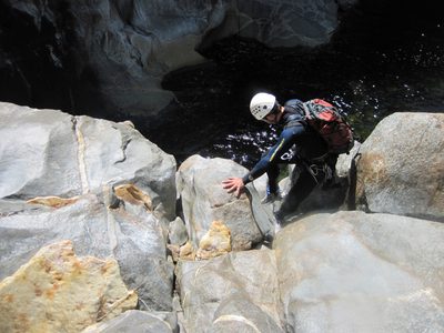 Colin down-climbs some boulders to regain the water...