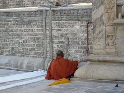A monk with a saffron parasol sits in meditation. 