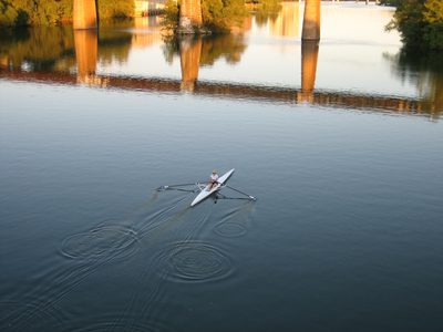 Skuller with Texas state flag oars on town lake.