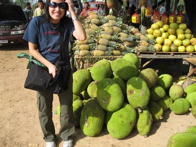 Helena poses in front of a pile of jack fruit at a...