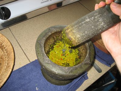 Using a mortar and pistil to make green curry.