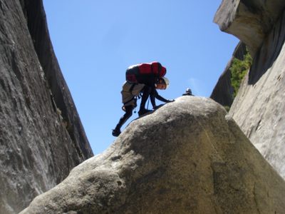 John climbing a boulder to find a rappel bolt.